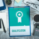 A desk with a clipboard reading 'qualification'